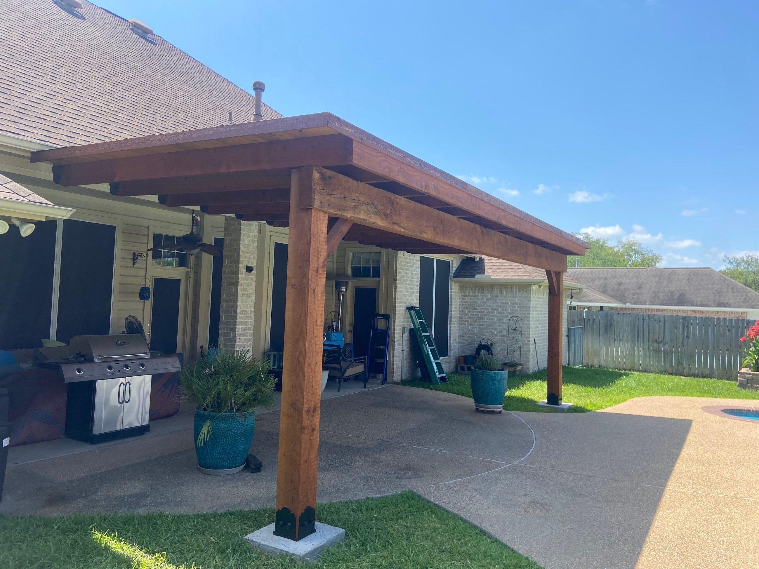 a Custom Patio Designed with a Pergola Cover and Curved Path Leading to the Pool