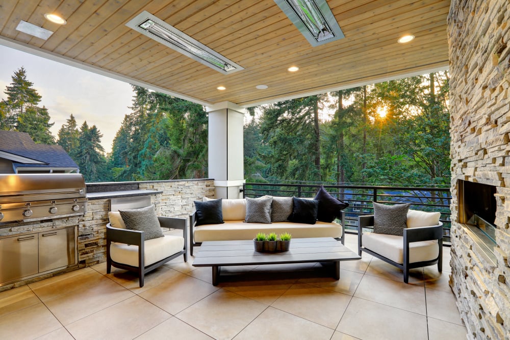 Luxury Modern House Exterior with Covered Patio Boasting Stone Fireplace and Cozy Rattan Furniture.