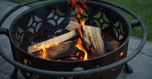 H3 blog images | h3 outdoor design & construction Traditional Wood Burning Firepit with Stacked Logs and Glowing Flames, Creating a Warm Outdoor Gathering Space