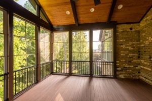 Modern screened porch enclosure with plastic windows and composite floor with summer woods in the background
