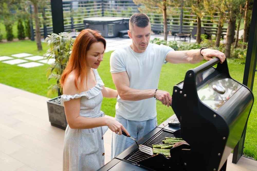 Two People Are Cooking Food on a Grill in a Backyard